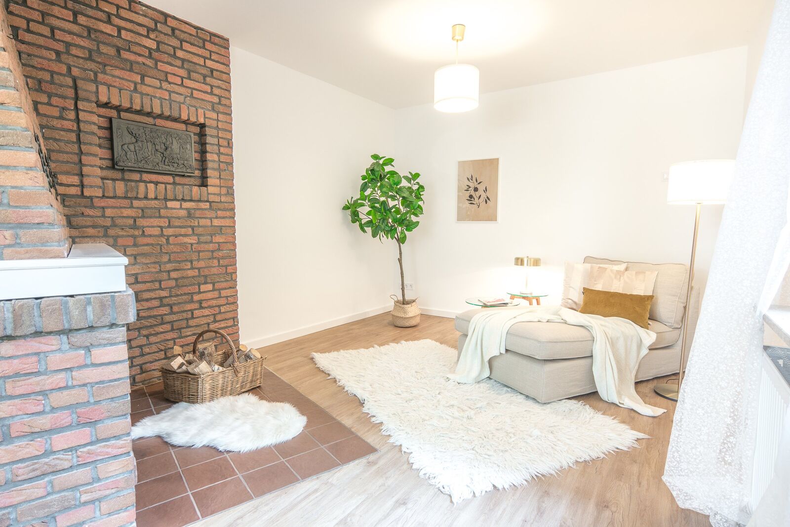 Hell eingerichtetes Wohnzimmer mit Backsteinkamin